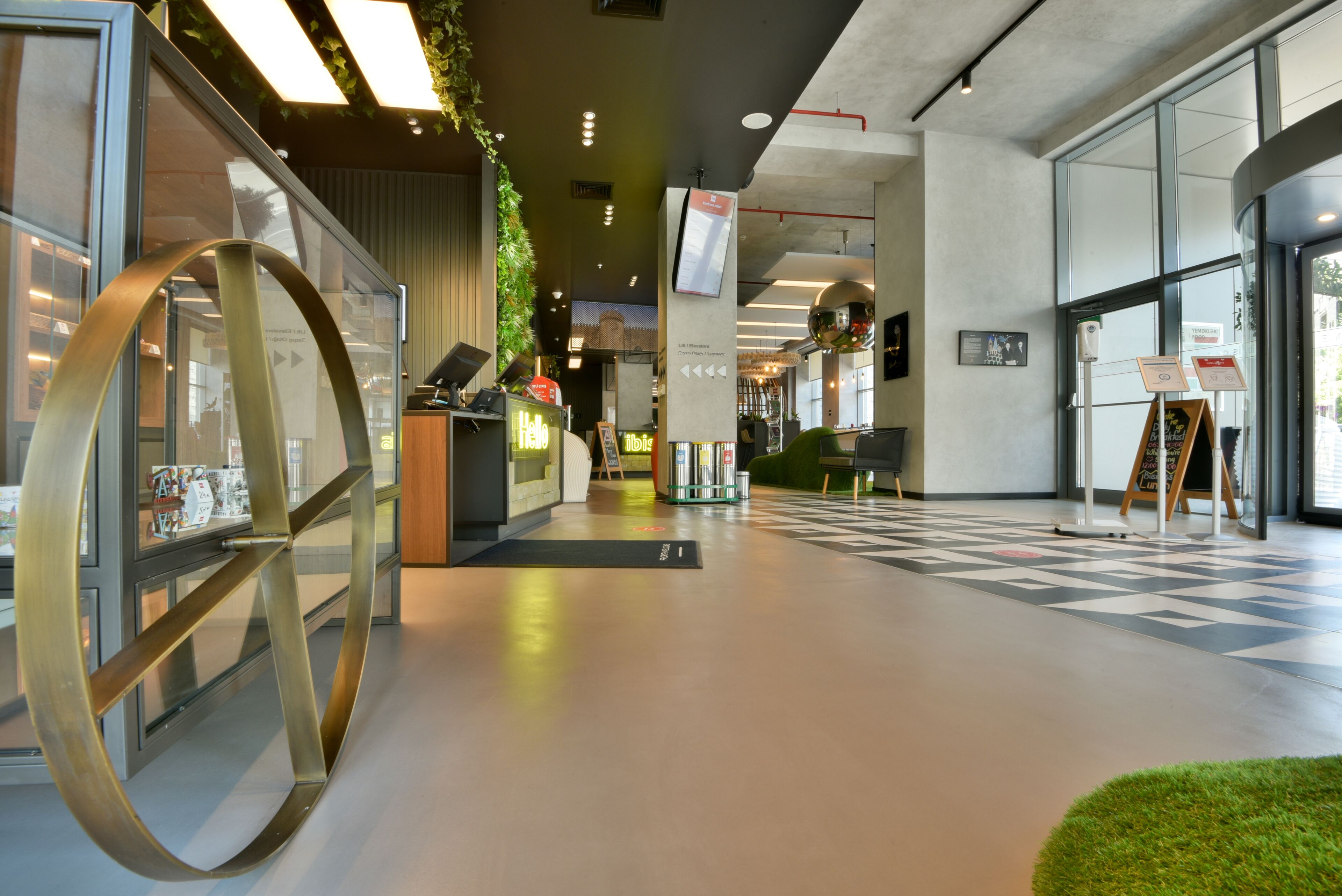 A modern interior with a reception desk, a large metallic sculpture, and a patterned floor.