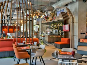 A modern restaurant with high ceilings, a bar area, and seating arrangements. - Ibis Baku City (Baku)
