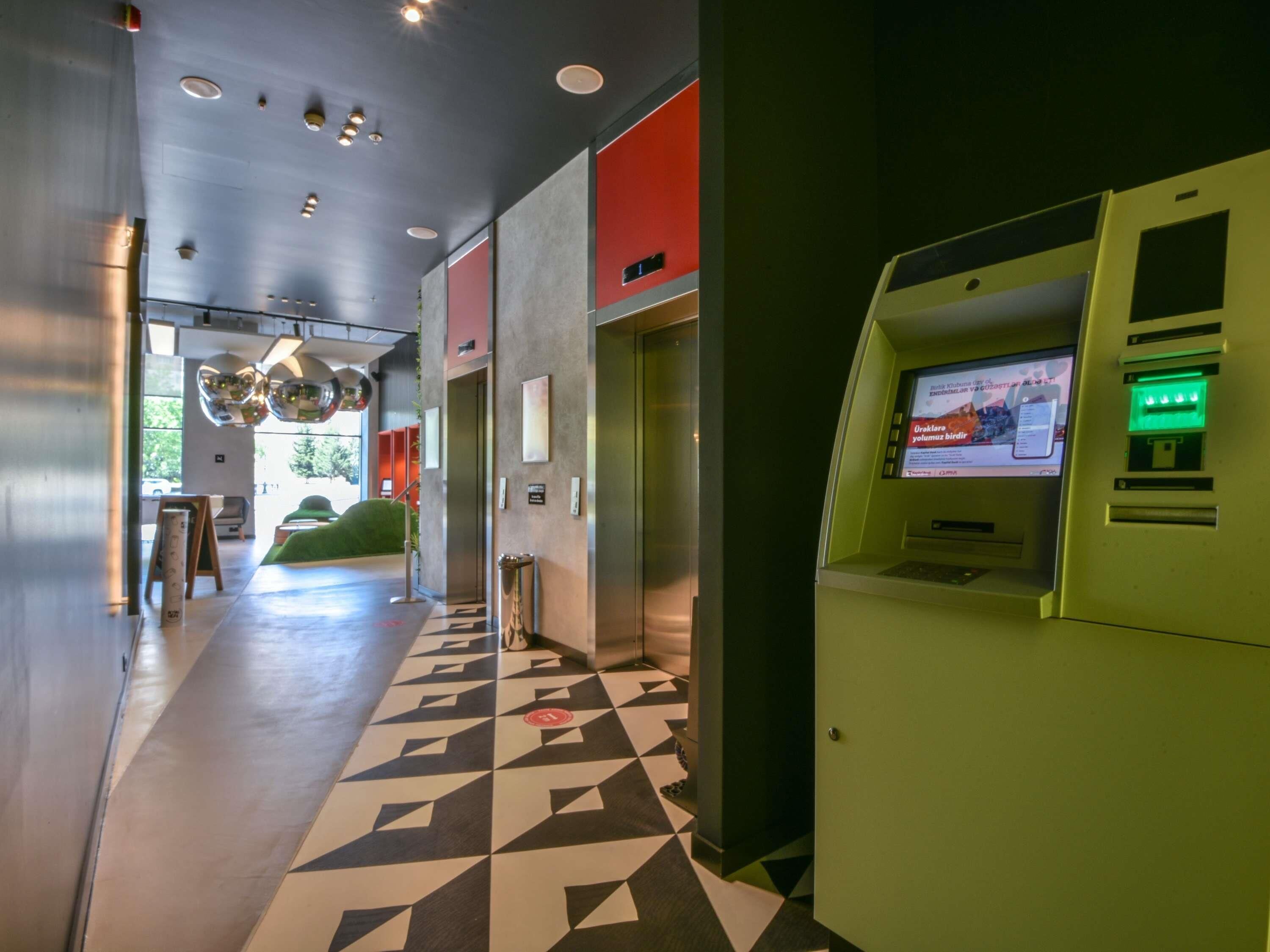 Un hall d’entrée moderne avec un sol à motifs géométriques, un comptoir d’accueil et un distributeur automatique de billets.