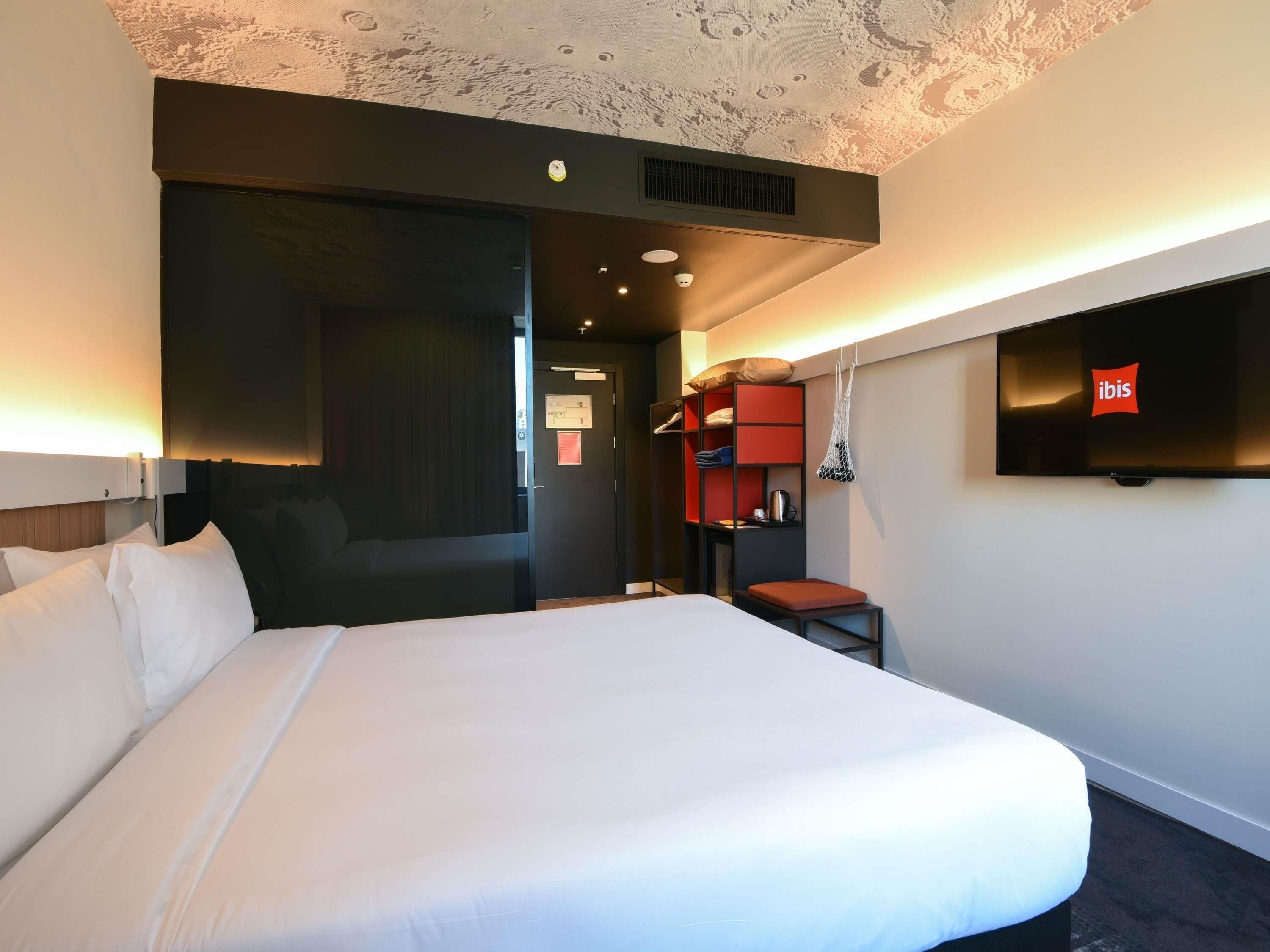 Habitación de hotel con una cama grande, televisión, armario y escritorio.