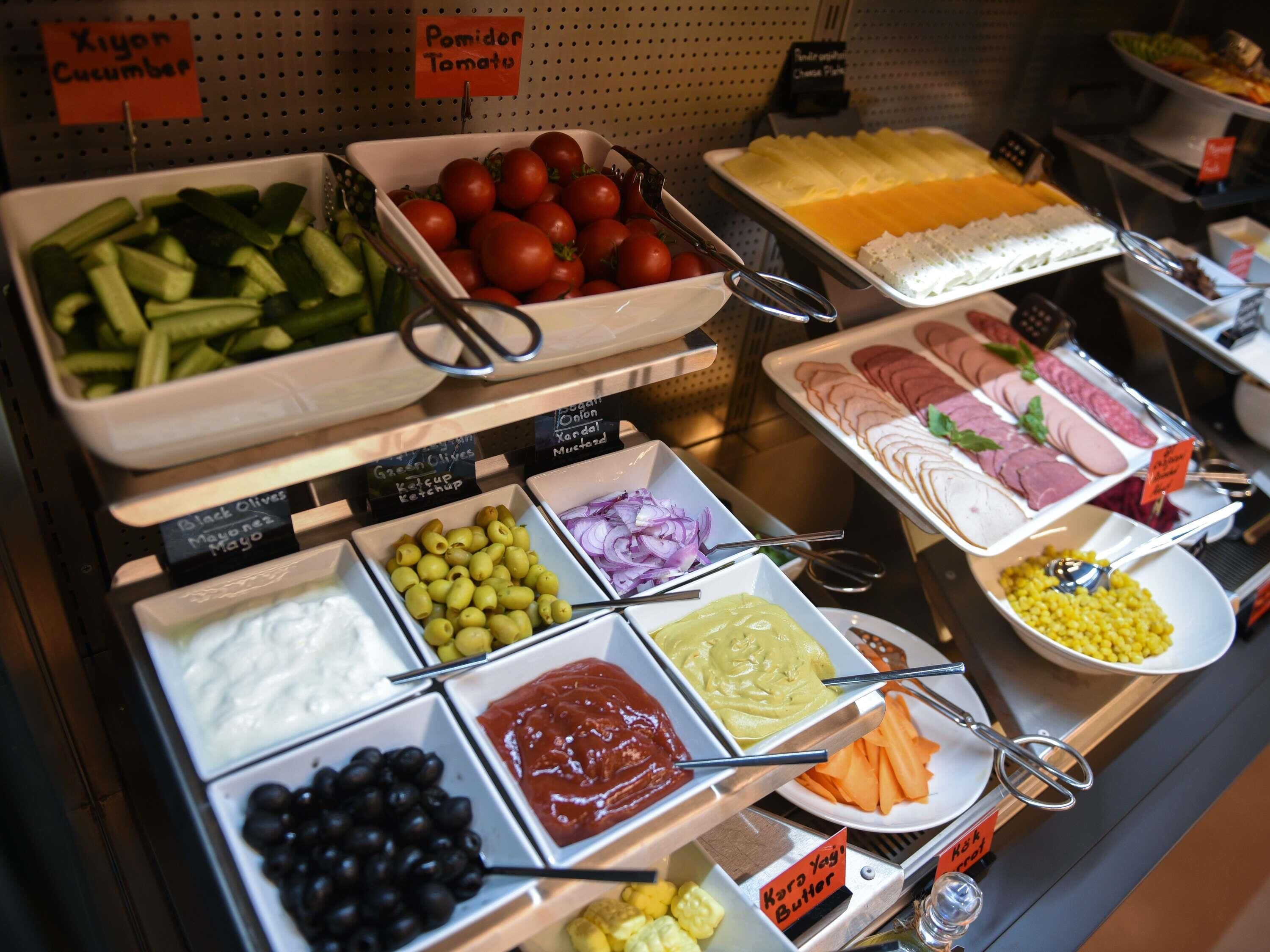 Een buffet met diverse soorten eten, waaronder groenten, kazen en vlees.