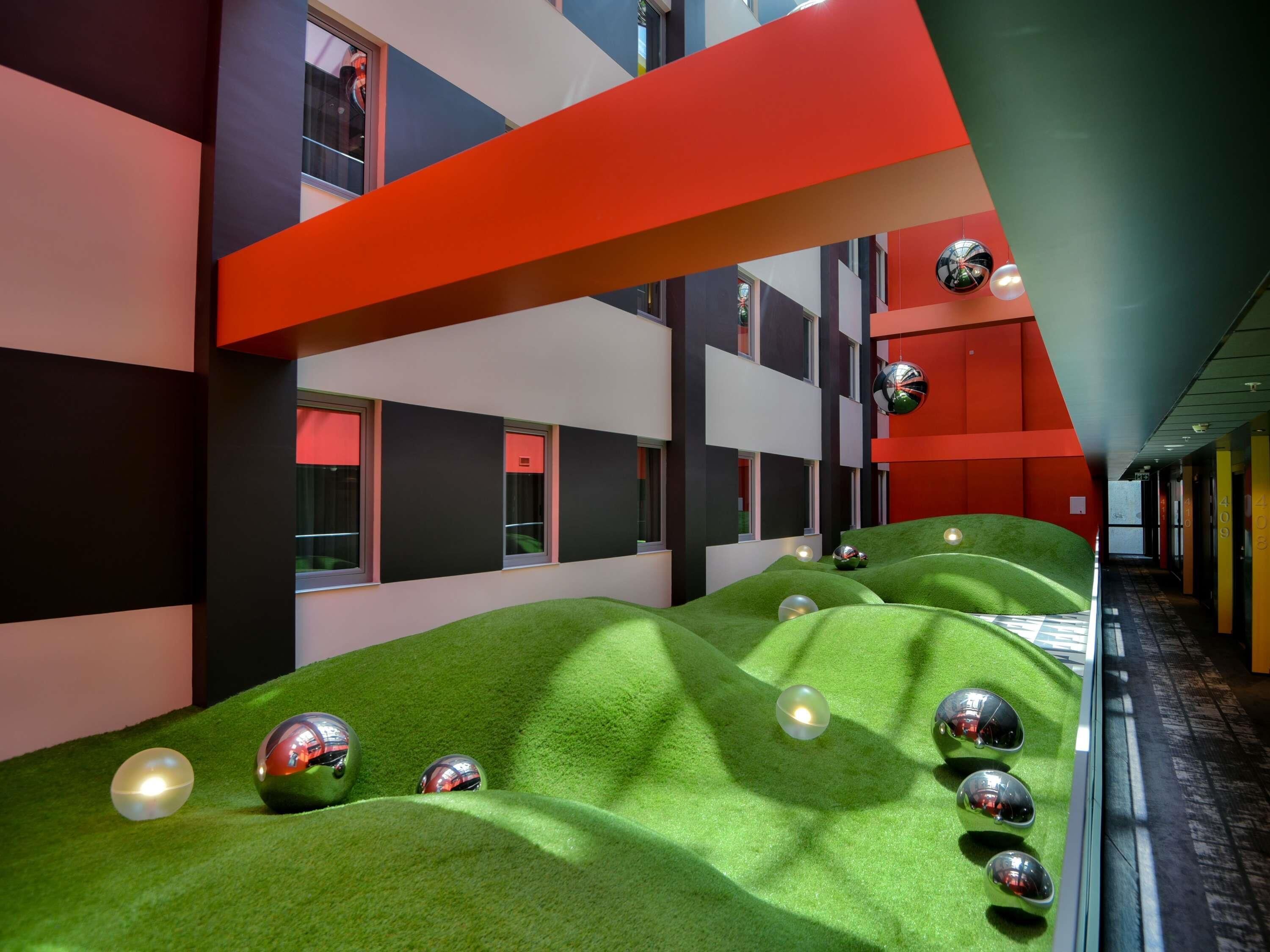 A modern interior with green artificial grass, reflective spheres, and geometric wall designs.