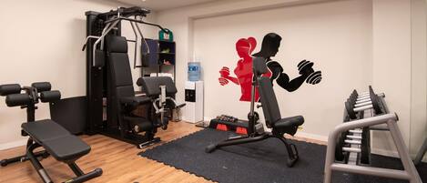 A gym with exercise equipment, a water dispenser, and a wall decoration.