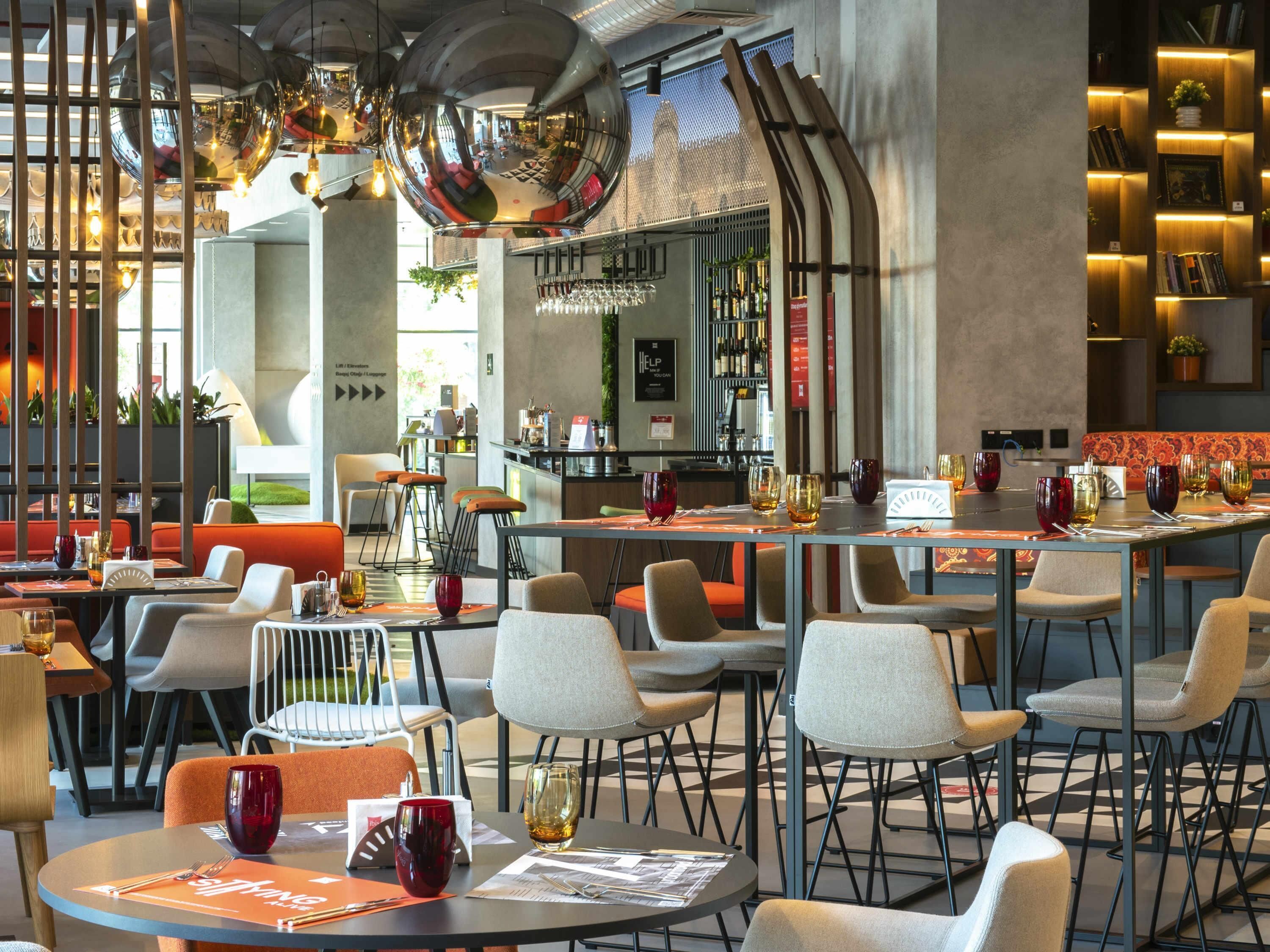 A modern restaurant interior with high ceilings, reflective disco balls, and a bar area.