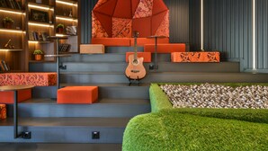 Un interior moderno con una escalera, asientos anaranjados, una guitarra y un adorno geométrico en la pared.