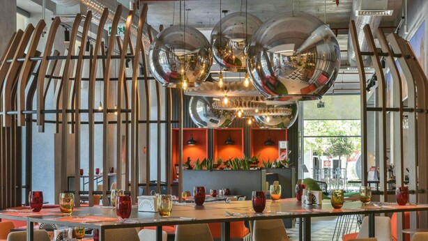 Un restaurante moderno con una larga mesa de comedor, numerosas sillas y un área central con bar.