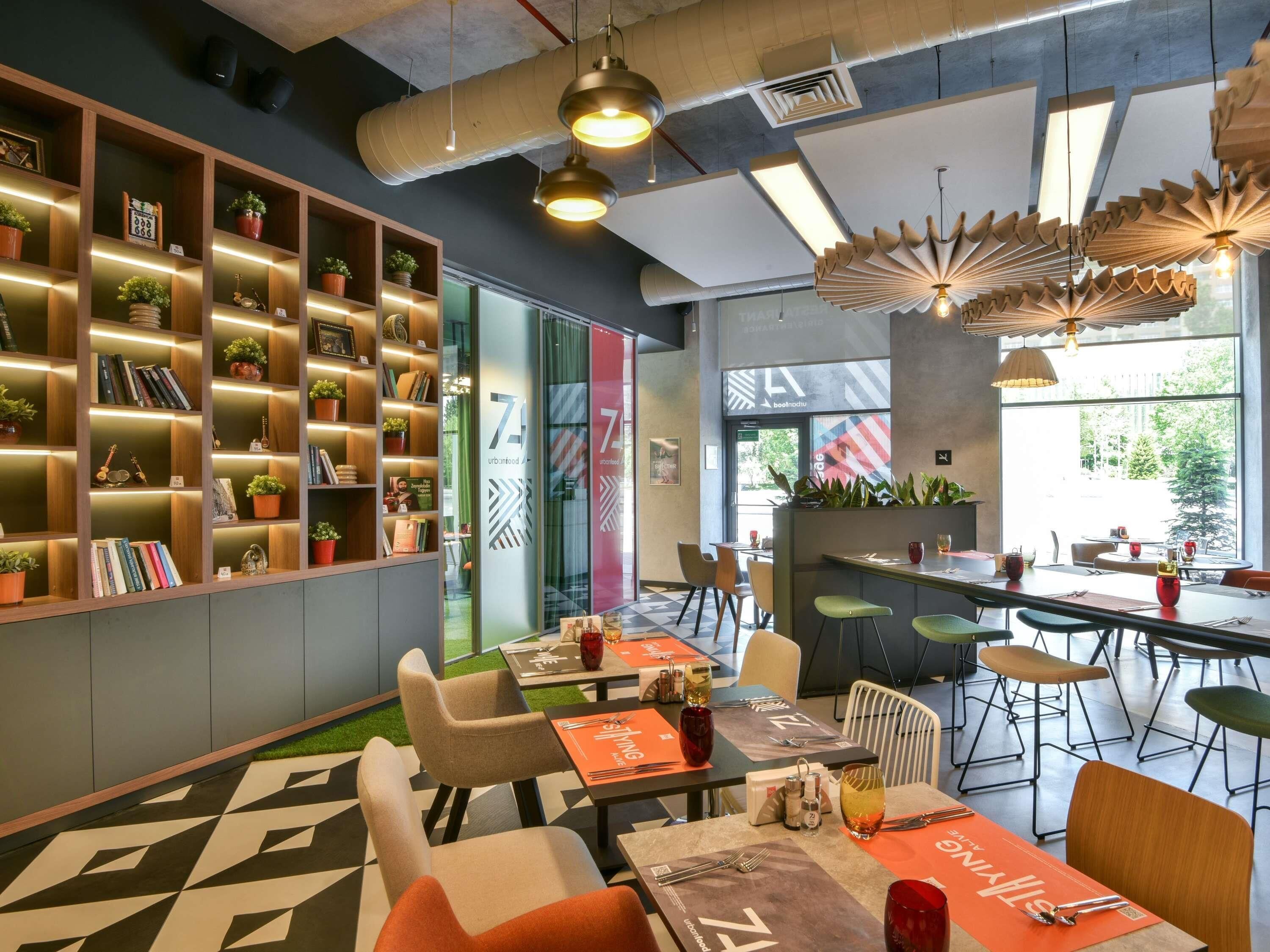 A modern interior with a bar area, seating, and a bookshelf with plants.