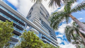 A modern high-rise building with multiple balconies and a clear sky.