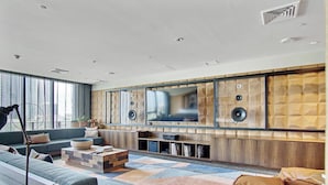 A modern living room with a large TV, built-in speakers, and a cozy seating area.