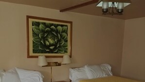 A hotel room with two beds, a nightstand, a lamp, and a ceiling light fixture.