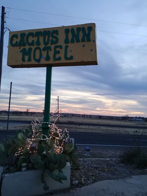 A sign for the Cactus Inn Motel with a green post and a cactus decoration.