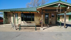 A small building with a green roof and a bench outside. - Cactus Inn (McLean)