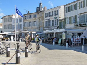 Ein gepflasterter Fußgängerbereich mit Fahrrädern, Außenbestuhlung und Geschäften mit Schildern für Restaurants und Bars.