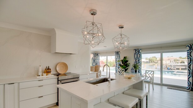 Cozinha moderna com ilha central, banquetas e iluminação pendente.