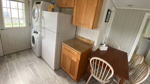 Une cuisine compacte dotée de meubles en bois, d’un lave-linge, d’un réfrigérateur et d’un coin repas avec une table et des chaises.