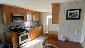 Une cuisine avec des meubles en bois, un four à micro-ondes, une cuisinière et une table à manger avec des chaises.