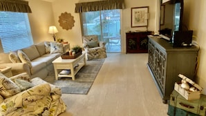 A living room with a sofa, coffee table, and a television on a cabinet. - Perfect Location 2/2 Villa in Creekside Landing walking distance to Lake Sumter (The Villages)