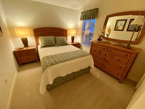 A neatly arranged bedroom with a bed, nightstands, a dresser, and a mirror. - Perfect Location 2/2 Villa in Creekside Landing walking distance to Lake Sumter (The Villages)