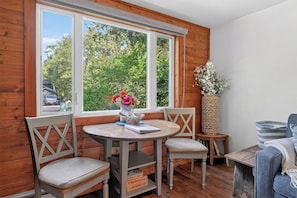A cozy corner with a round table, two chairs, a woven basket, and a view of greenery outside. - Cabin in Downtown Ephraim-Perfect for couples! (Ephraim)