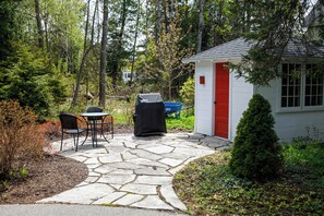 A stone patio with outdoor furniture, a small shed, and a coniferous tree. - Cabin in Downtown Ephraim-Perfect for couples! (Ephraim)
