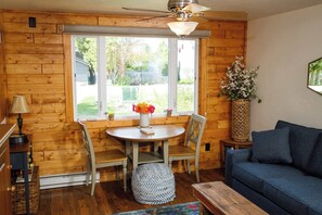 Un interior de madera con una mesa de comedor, sillas, un sofá y una ventana que ofrece vistas al exterior.
