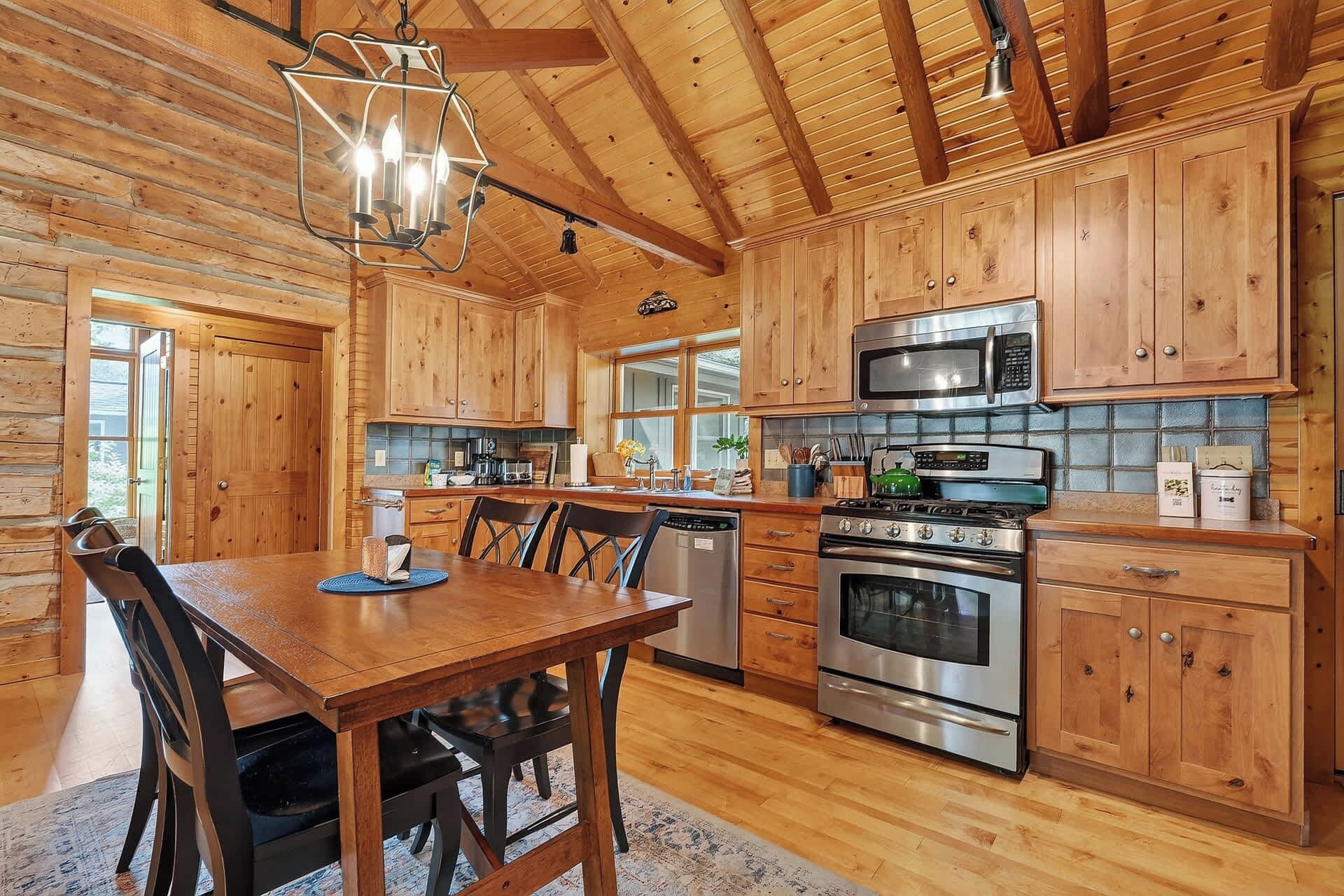 Una cocina de madera con una mesa de comedor, sillas, estufa, horno, microondas y armarios.