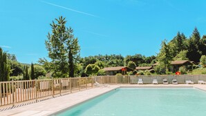 Ein rechteckiger Pool mit gefliestem Sonnendeck, umgeben von einem Holzzaun.