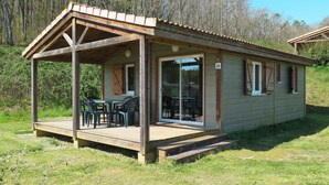 Eine kleine, eingeschossige Holzhütte mit einer Veranda und einer Glasschiebetür.