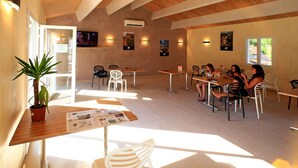 A spacious indoor dining area with natural light, white chairs, and tables. - Cosy apartment in villa for 6 guests with WIFI, pool, TV, terrace and pets allowed (Cazals)