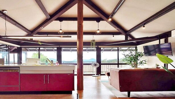 A modern kitchen with a central island, red cabinets, and a large window offering a view of the outdoors. - IzuRicca (Izunokuni)