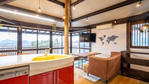 A modern kitchen with a yellow sink, red cabinets, and a view of mountains through large windows. - IzuRicca (Izunokuni)