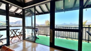 A room with large windows, a wooden floor, and a green outdoor area with a view of mountains. - IzuRicca (Izunokuni)