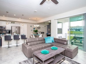 Relax in this stylish living area with a sofa, ottoman, and dining space, offering a balcony with a view.