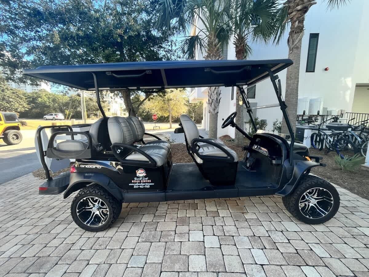 A golf cart parked on a paved area with a building in the background.