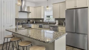 A modern kitchen with granite countertops, stainless steel appliances, and pendant lighting.