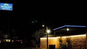 A modern motel with a prominent sign, a well-lit exterior, and a brick facade.