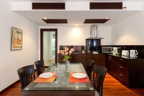 Una cocina moderna con armarios de madera oscura, una campana extractora de acero inoxidable y un comedor de vidrio con platos y cubiertos.