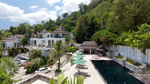 Un resort con múltiples villas, piscina y abundante vegetación.