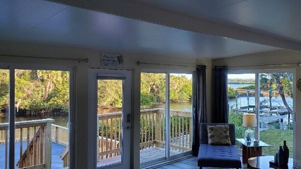 Un espace extérieur abrité avec vue sur un lac et un quai, comprenant un canapé et une table avec une lampe.