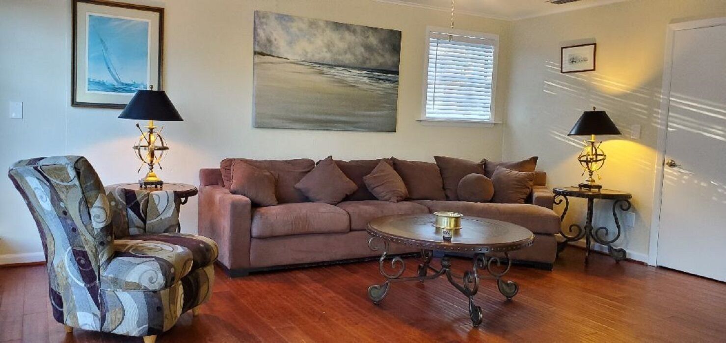 Uma sala de estar com sofá, poltrona e mesa de centro redonda.