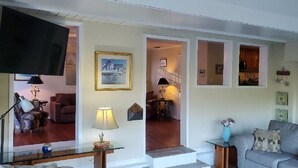 Un salon comprenant un canapé, une table basse, un téléviseur et un escalier menant à une autre pièce.