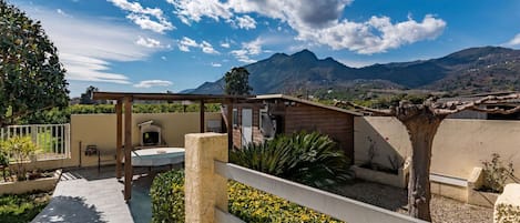 A patio with a barbecue, seating, and a view of mountains.