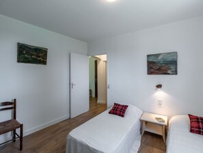 A bedroom with two beds, a wooden chair, a desk with a lamp, and a painting on the wall. - Nice apartment for 4 people with A/C, WIFI, TV, terrace, pets allowed and panoramic view (Prunete)