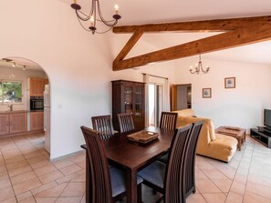 Amplia sala de estar con una mesa de comedor de madera, sillas, un sofá y un televisor.