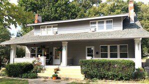 Une maison à deux étages avec un porche à l’avant, une cheminée et une boîte aux lettres.
