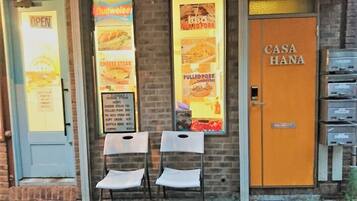 A restaurant with a blue door, a Coca-Cola sign, and a menu board advertising pulled pork sandwiches.