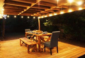 Eine hölzerne Terrasse im Freien mit einem Esstisch und Stühlen.