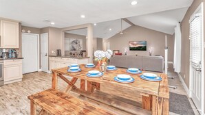 Une cuisine spacieuse avec un coin repas comprenant une table en bois dressée pour quatre personnes.