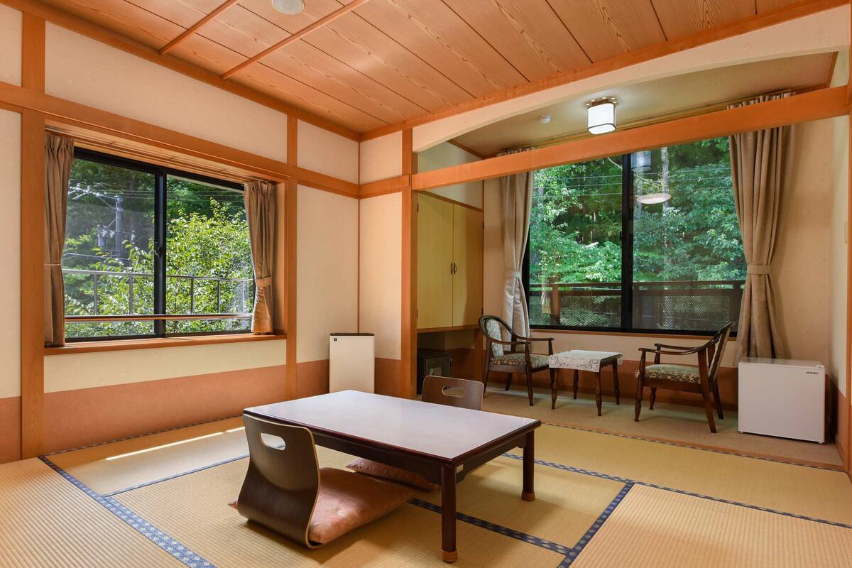 A traditional Japanese room with tatami flooring, a low table, and a chair.