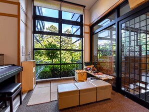 A room with a large window, a piano, a wooden cabinet, and a small table with toys. - Suzuranso (Komagane)